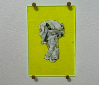a yellow piece of art hanging on a wall